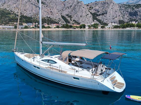 Sun Odyssey 42 DS anchored in a turquoise bay with coastal mountains