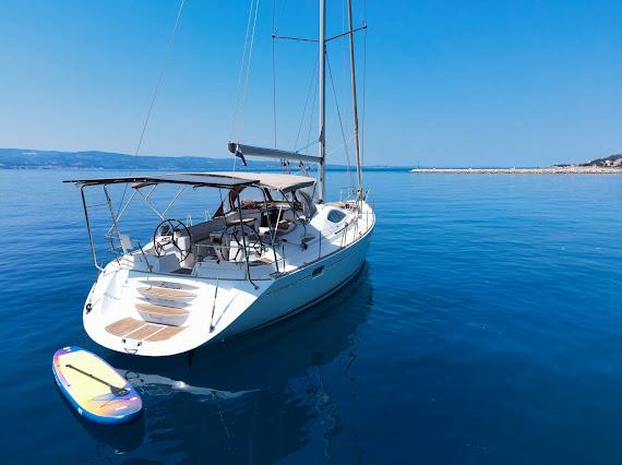 Yacht stern with paddleboard on calm blue water